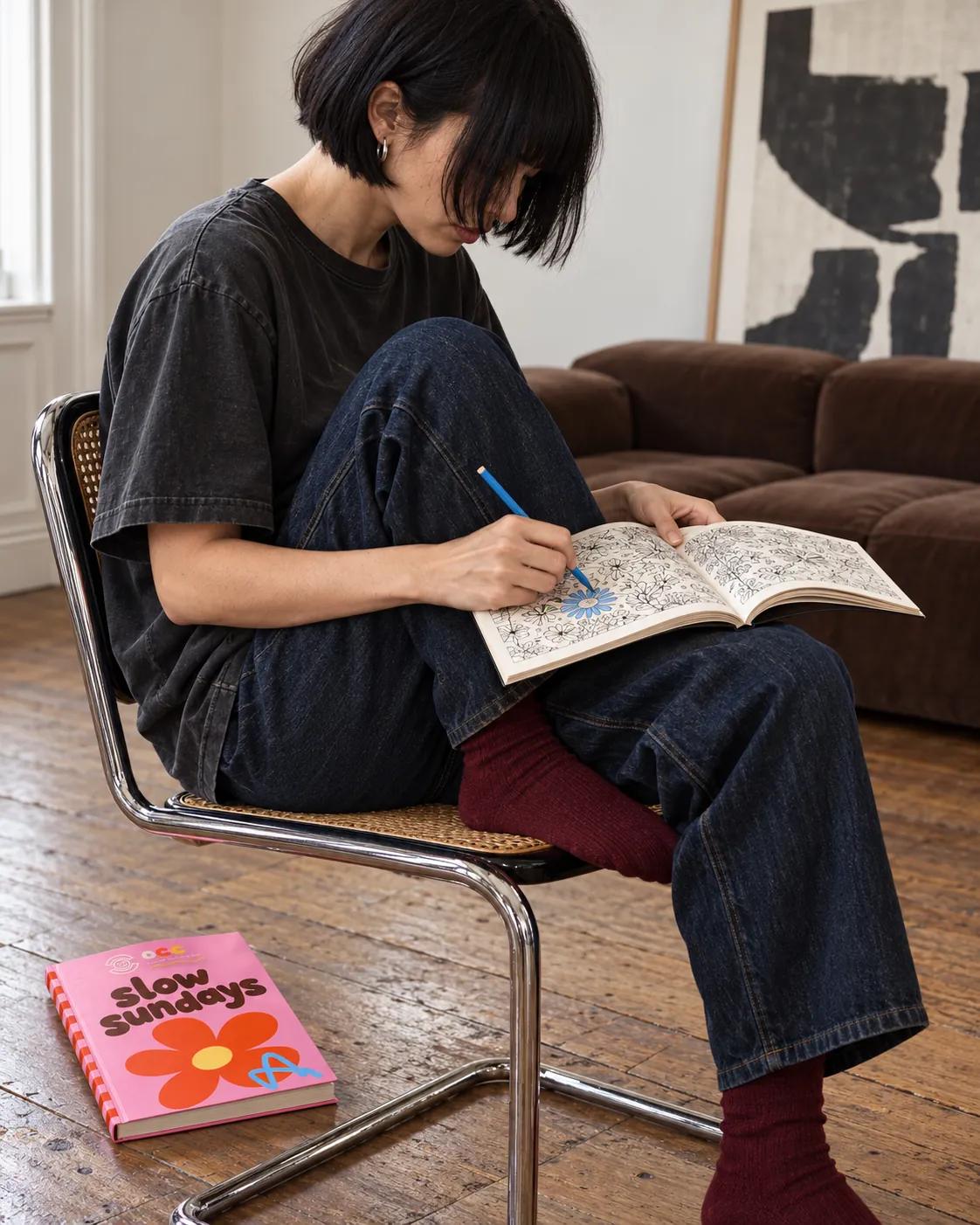 Someone colouring on a chair, slow sundays on the floor beside them